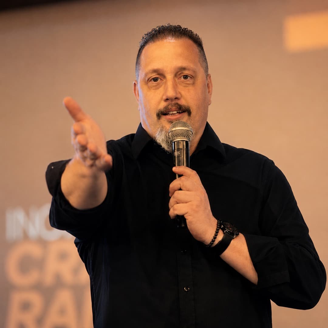 Luciano Passaretti palestrando em evento, gesticulando com a mão